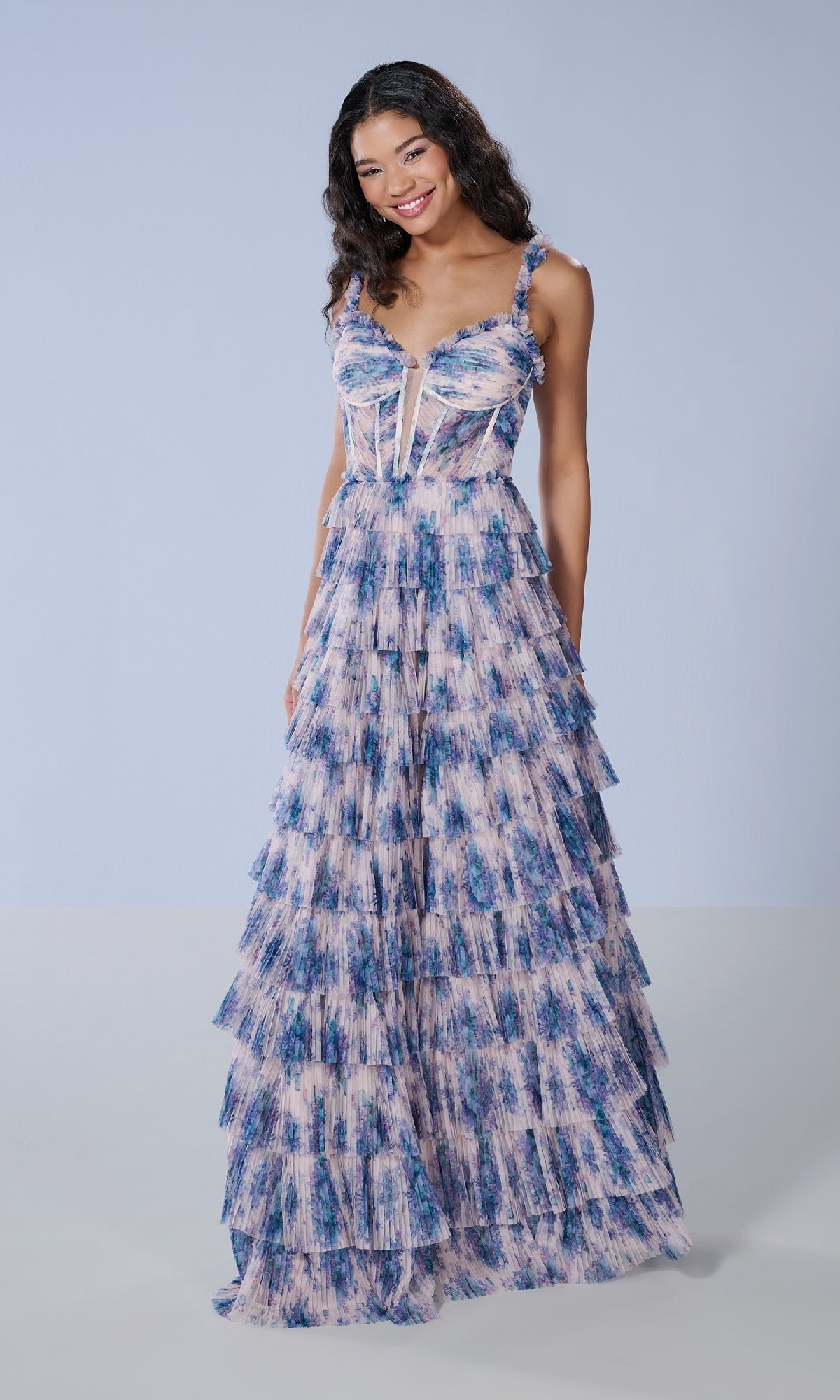 A woman wears the Tiffany 16160 long prom dress, a sleeveless, floor-length A-line gown with blue and pink abstract patterns, standing against a plain light background.